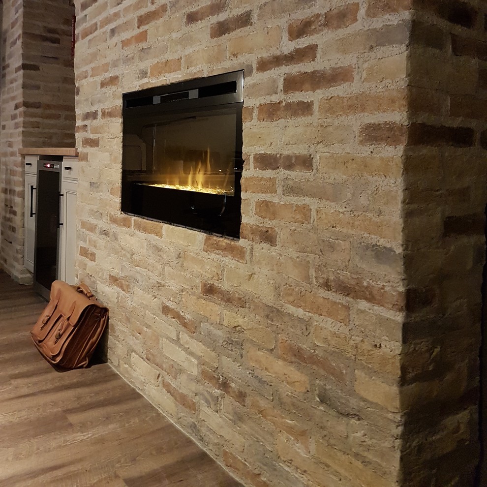 Réalisation d'un sous-sol tradition enterré et de taille moyenne avec un sol en vinyl, une cheminée standard, un manteau de cheminée en brique et un sol marron.