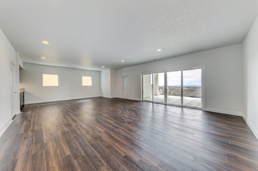This is an example of a large modern walk-out basement in Seattle with white walls, medium hardwood flooring and no fireplace.