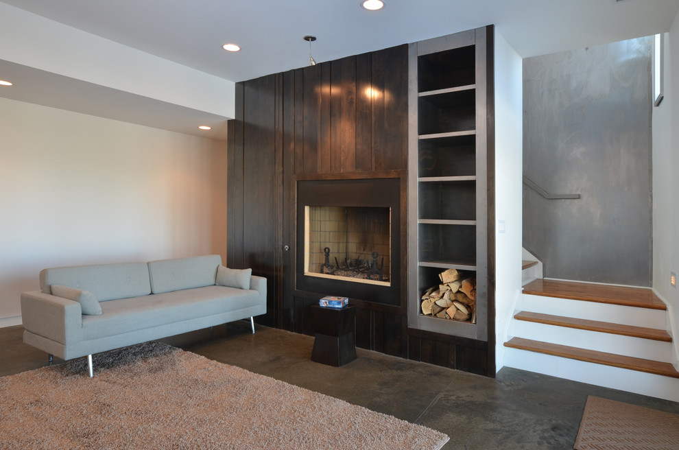Medium sized modern look-out basement in Charlotte with white walls, concrete flooring, a standard fireplace and grey floors.
