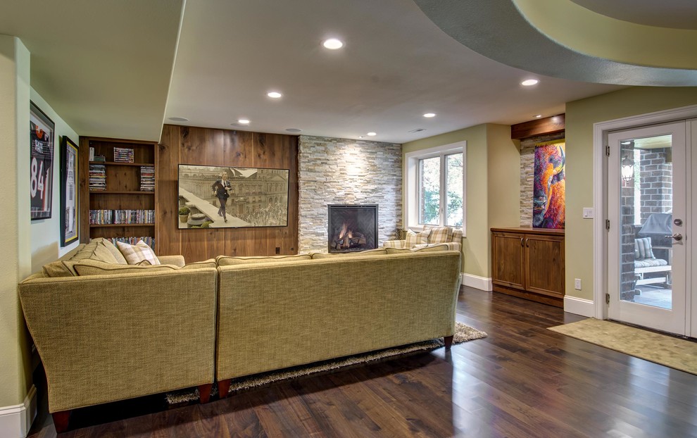 Basement - large traditional walk-out medium tone wood floor and brown floor basement idea in Denver with green walls, a standard fireplace and a stone fireplace