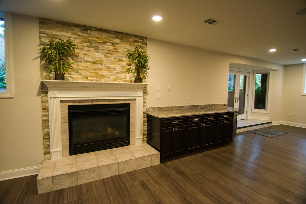 Design ideas for a large traditional walk-out basement in Detroit with grey walls, vinyl flooring, a standard fireplace and a stone fireplace surround.