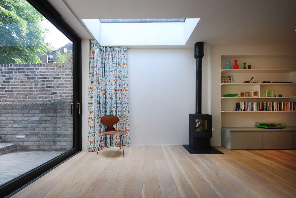 Réalisation d'un sous-sol design de taille moyenne avec un mur blanc, parquet clair et un poêle à bois.
