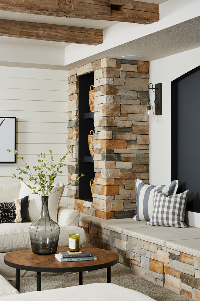 Inspiration pour un sous-sol rustique donnant sur l'extérieur et de taille moyenne avec un mur blanc, moquette, une cheminée d'angle, un manteau de cheminée en pierre et un sol gris.