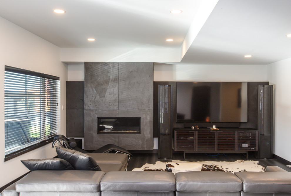 This is an example of a contemporary walk-out basement in Other with a home cinema, white walls, laminate floors, a standard fireplace, a concrete fireplace surround, grey floors and a drop ceiling.