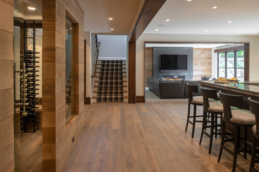 Inspiration for a large rustic walk-out medium tone wood floor and brown floor basement remodel in Minneapolis with white walls, a standard fireplace and a metal fireplace