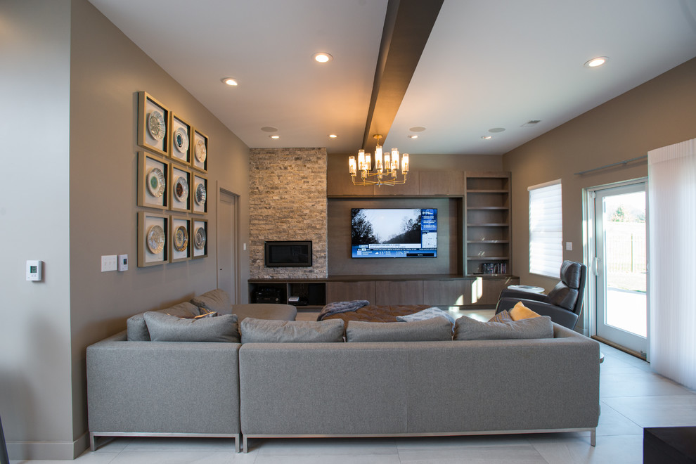 Photo of a large modern walk-out basement in Other with beige walls, a ribbon fireplace, a stone fireplace surround and grey floors.