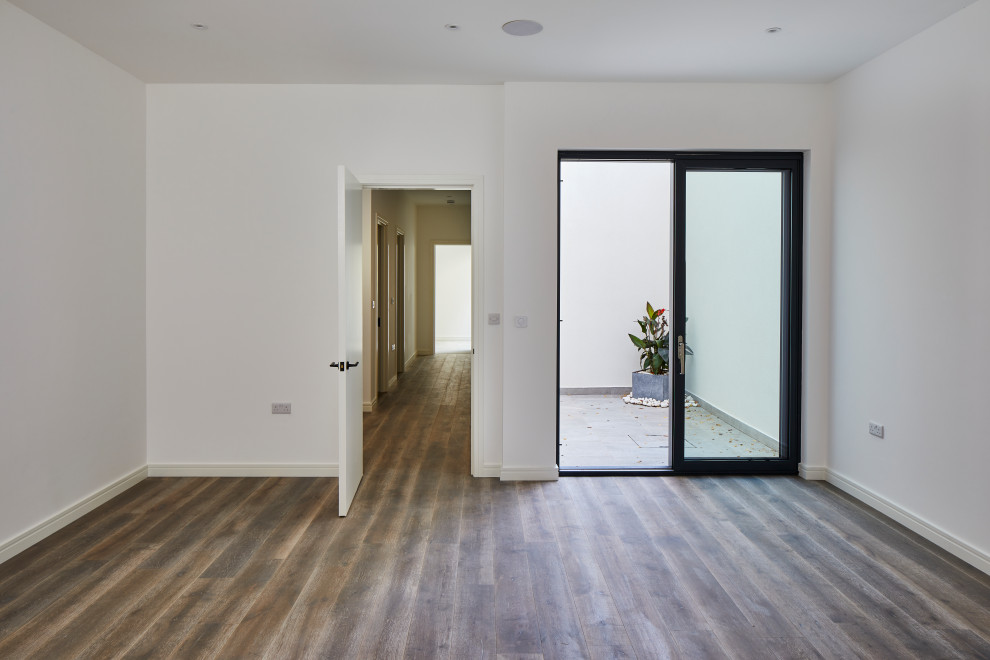 Design ideas for a large modern walk-out basement in London with white walls, medium hardwood flooring and brown floors.