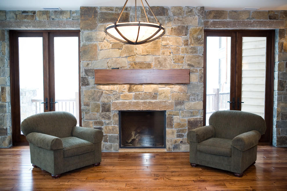 Large mountain style medium tone wood floor basement photo in Salt Lake City with beige walls, a standard fireplace and a stone fireplace