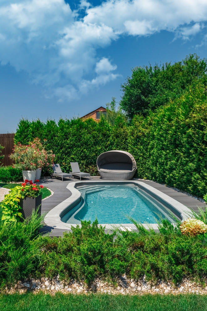 Exemple d'une piscine latérale tendance en forme de haricot avec une terrasse en bois.