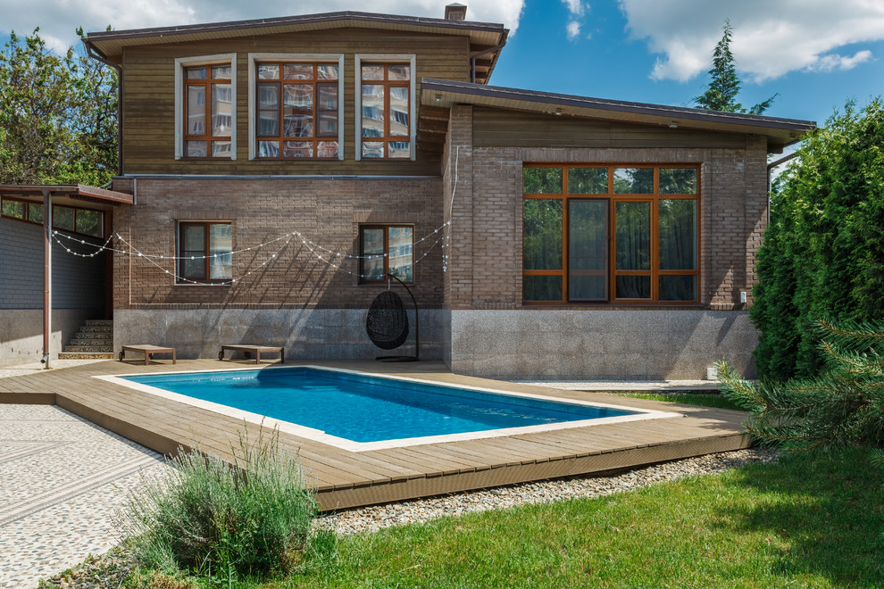 Ejemplo de piscina alargada tradicional renovada rectangular en patio delantero con entablado