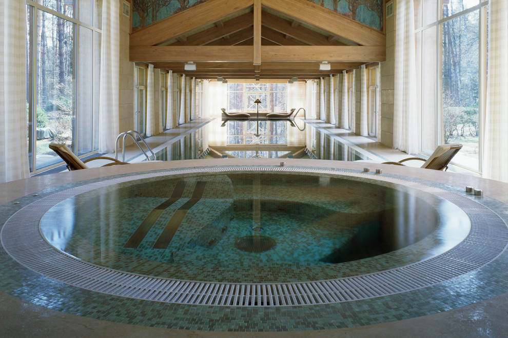 Réalisation d'une grande piscine intérieure ronde avec un bain bouillonnant.