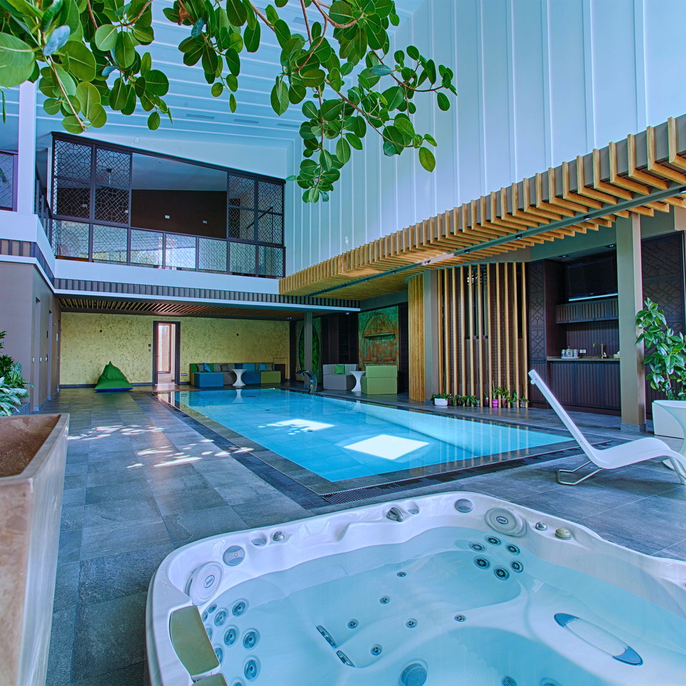 Idée de décoration pour une grande piscine intérieure à débordement urbaine rectangle avec un bain bouillonnant et du carrelage.
