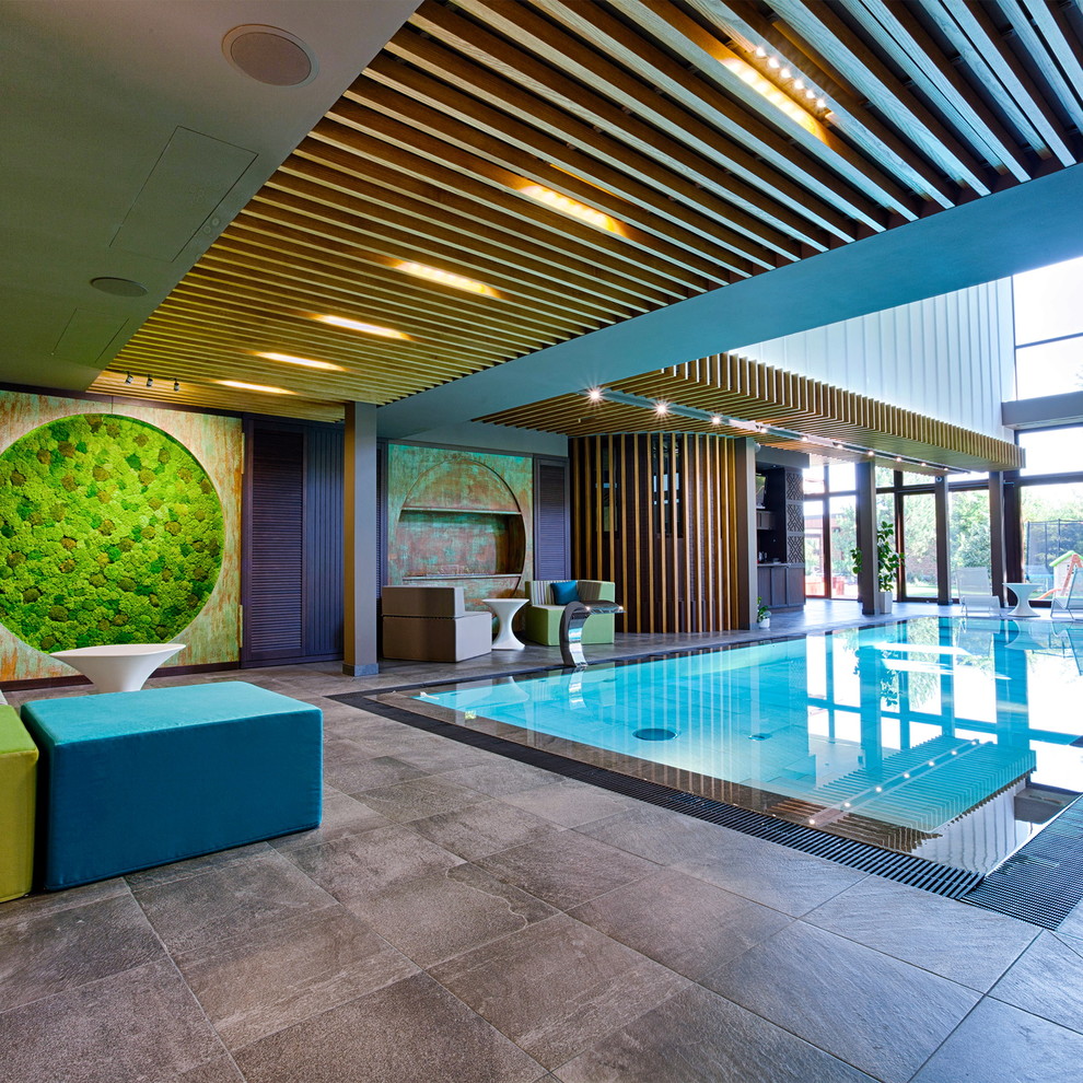 Inspiration for a large industrial indoor rectangular infinity swimming pool with a water feature and tiled flooring.