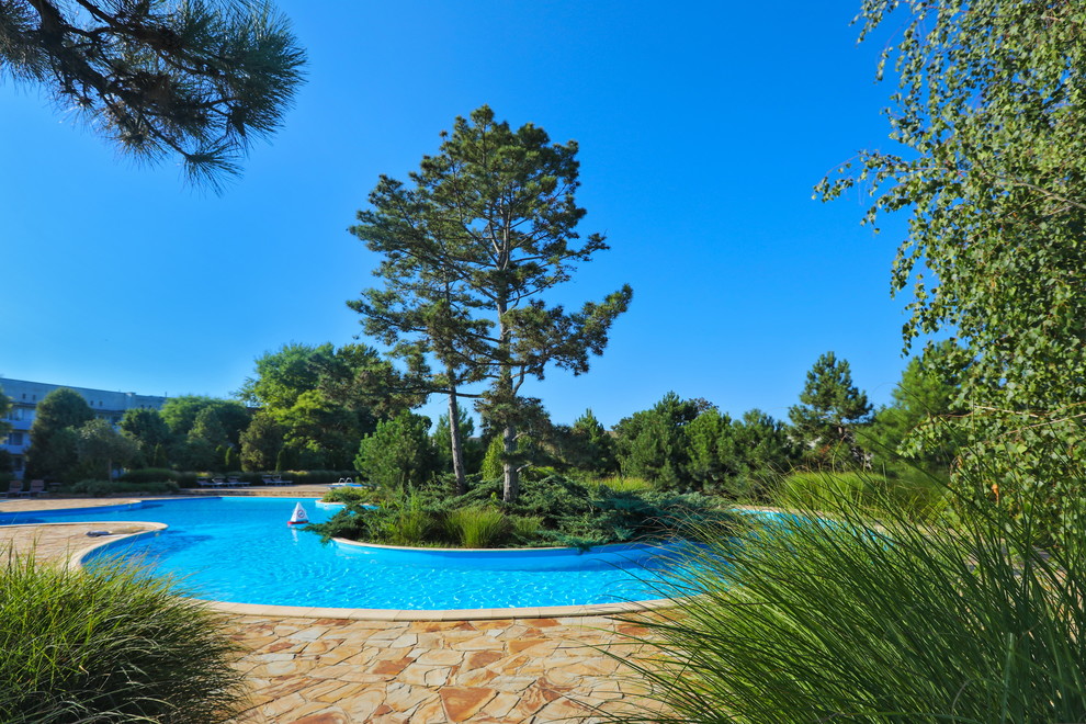 Réalisation d'une grande piscine hors-sol méditerranéenne sur mesure avec une cour et des pavés en béton.