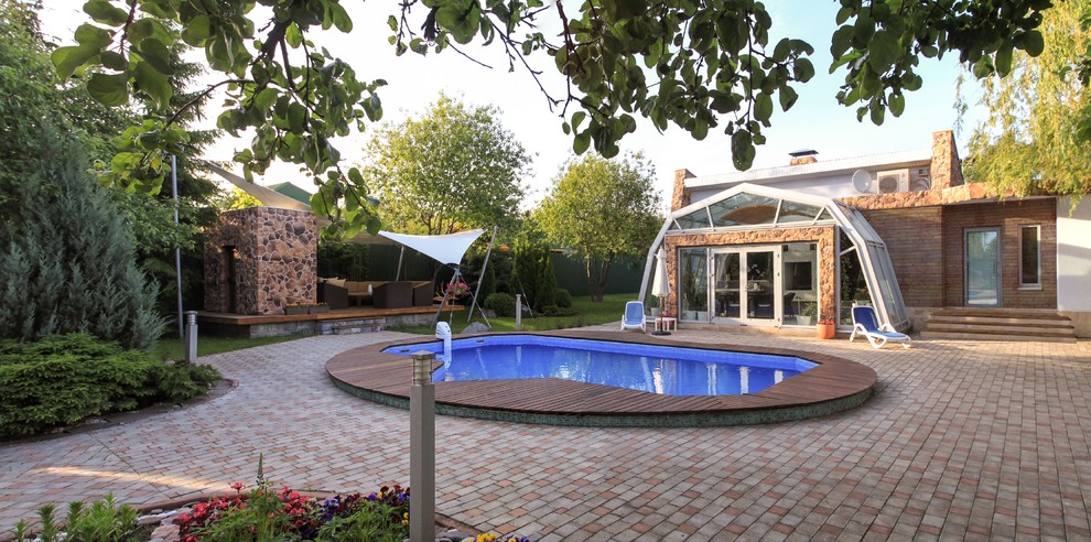 Ejemplo de piscina alargada contemporánea grande a medida en patio trasero con adoquines de ladrillo