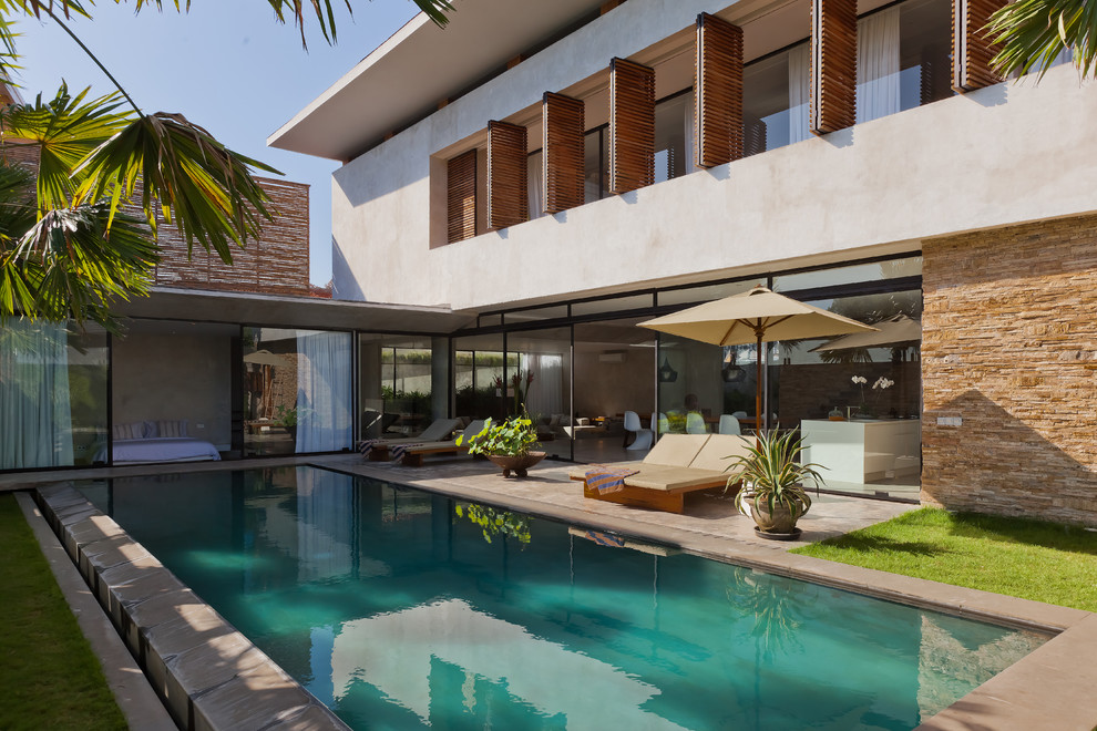 Diseño de piscina alargada actual rectangular en patio trasero con losas de hormigón