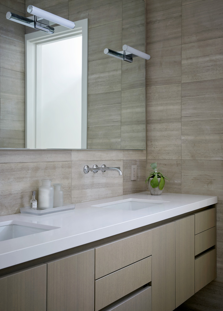 Inspiration pour une salle de bain design en bois clair avec un placard à porte plane, un carrelage beige, un mur beige, un lavabo encastré et un plan de toilette blanc.