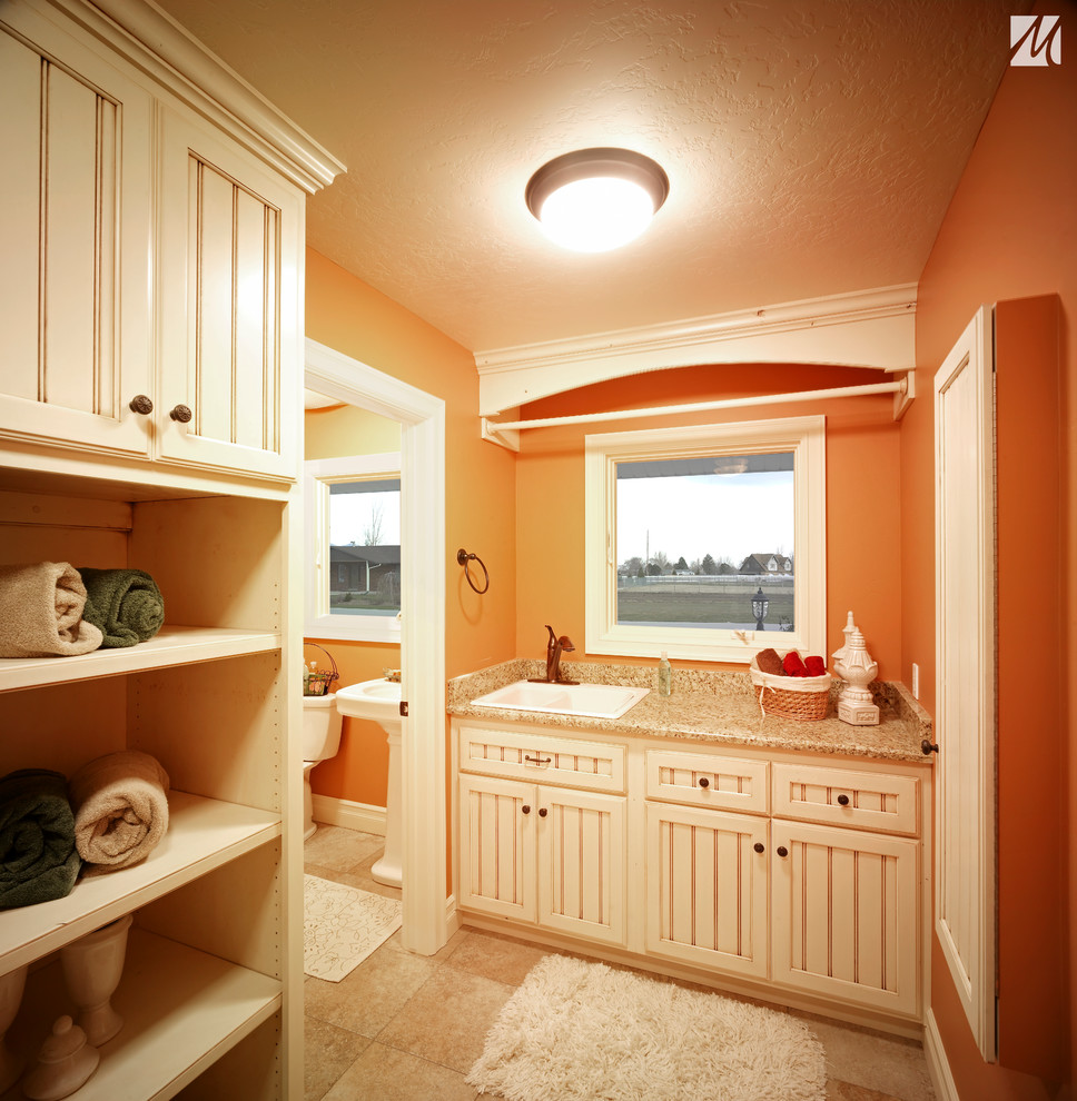 Cette image montre une petite salle de bain traditionnelle avec un lavabo posé, un placard à porte affleurante, des portes de placard blanches, un plan de toilette en granite, WC séparés, un carrelage beige, des carreaux de céramique, un mur orange et un sol en carrelage de céramique.
