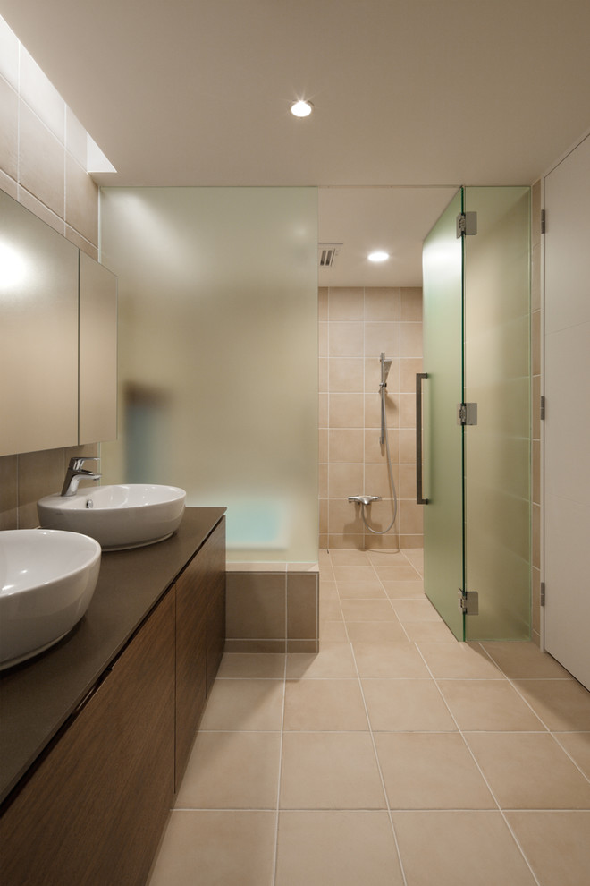 Inredning av ett modernt badrum, med en kantlös dusch, beige väggar, ett fristående handfat, släta luckor, bruna skåp, ett badkar i en alkov, rosa kakel och beiget golv