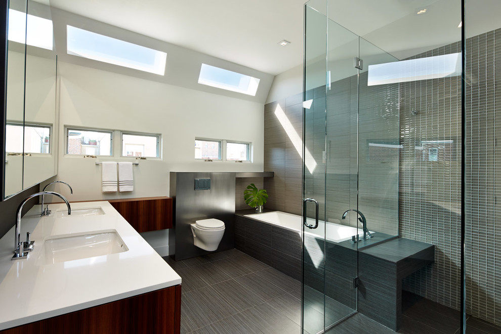 Exemple d'une salle de bain tendance en bois foncé avec un lavabo encastré, une baignoire posée, une douche d'angle, WC suspendus, un carrelage gris et mosaïque.