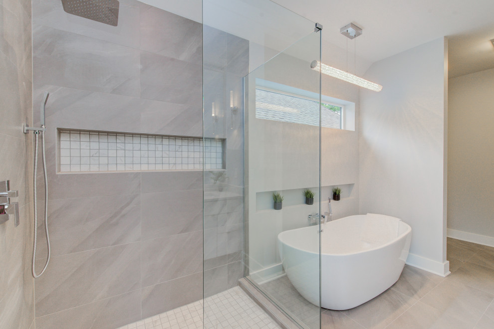 Inspiration for a medium sized traditional ensuite wet room bathroom in Indianapolis with flat-panel cabinets, white cabinets, a freestanding bath, a one-piece toilet, grey tiles, ceramic tiles, grey walls, porcelain flooring, a built-in sink, marble worktops, grey floors, a hinged door and white worktops.