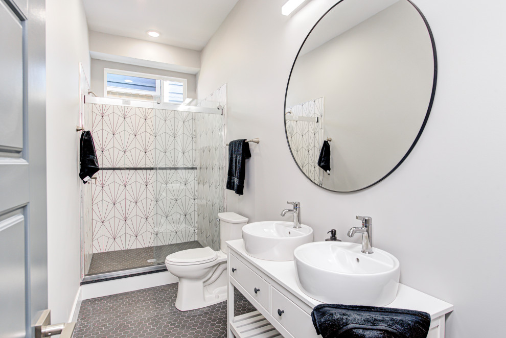 На фото: ванная комната среднего размера в стиле неоклассика (современная классика) с открытыми фасадами, белыми фасадами, душем в нише, унитазом-моноблоком, черно-белой плиткой, керамической плиткой, белыми стенами, полом из керамической плитки, душевой кабиной, настольной раковиной, столешницей из искусственного камня, серым полом, душем с раздвижными дверями, белой столешницей, тумбой под две раковины и напольной тумбой