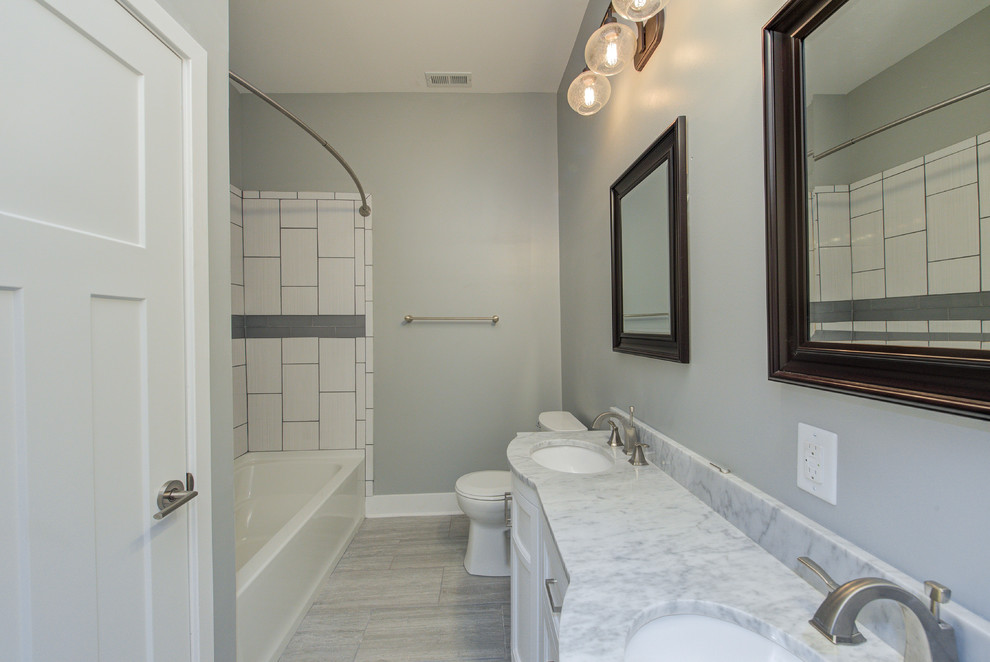 На фото: главная ванная комната среднего размера в стиле неоклассика (современная классика) с плоскими фасадами, белыми фасадами, унитазом-моноблоком, серыми стенами, полом из керамогранита, накладной раковиной, серым полом, белой столешницей, накладной ванной, душем над ванной, белой плиткой, керамической плиткой, мраморной столешницей и шторкой для ванной