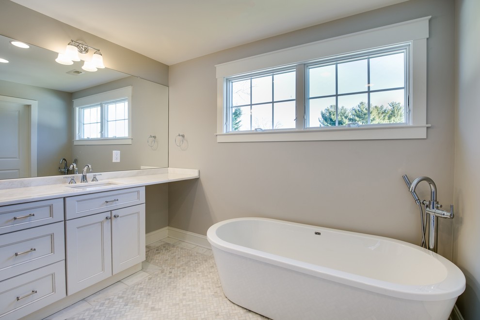 Example of a large transitional master white tile white floor and marble floor freestanding bathtub design in Philadelphia with recessed-panel cabinets, white cabinets, beige walls and an undermount sink
