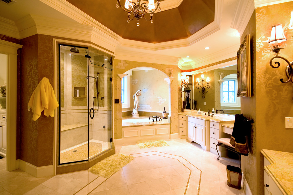 На фото: огромная главная ванная комната в классическом стиле с фасадами с выступающей филенкой, белыми фасадами, накладной ванной, душем в нише, коричневыми стенами, полом из керамогранита, врезной раковиной, столешницей из известняка, бежевым полом и душем с распашными дверями
