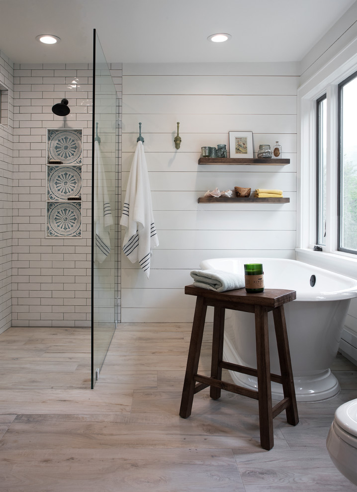 This is an example of a medium sized country ensuite bathroom in New York with dark wood cabinets, a freestanding bath, a built-in shower, white tiles, metro tiles, white walls, light hardwood flooring, a submerged sink, beige floors, an open shower and black worktops.