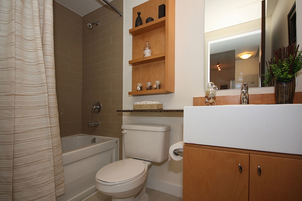 Photo of a small modern bathroom in Toronto with flat-panel cabinets, an alcove bath, a shower/bath combination, a two-piece toilet, beige walls, porcelain flooring, a built-in sink, light wood cabinets, laminate worktops, beige tiles and porcelain tiles.