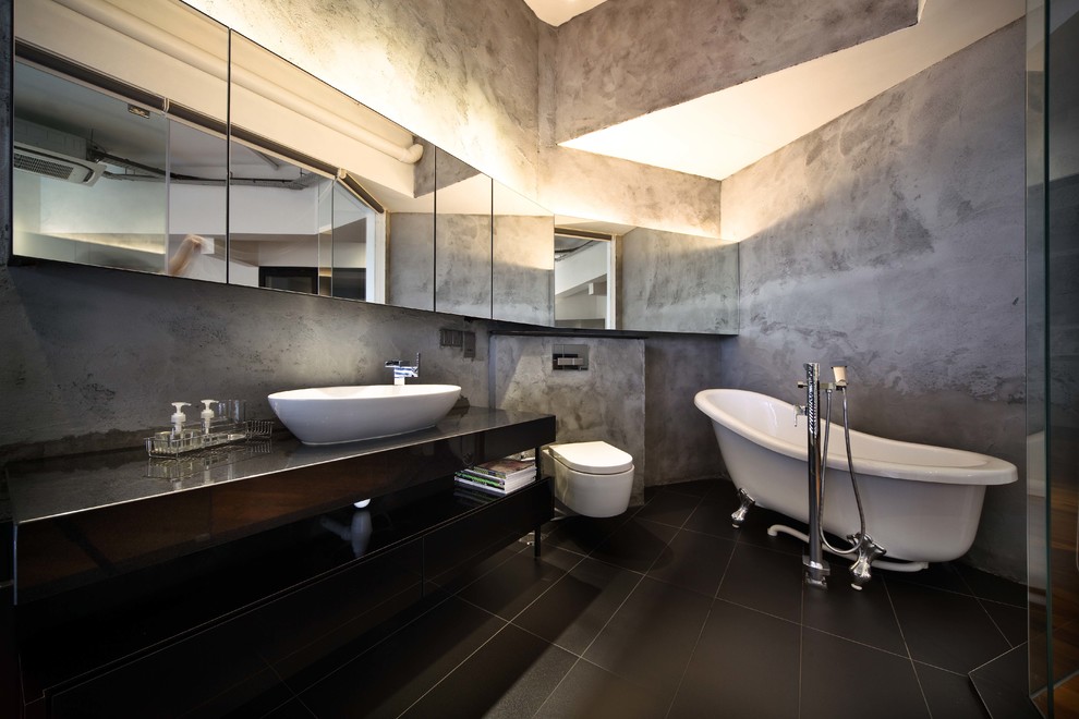 Aménagement d'une salle de bain contemporaine avec une vasque, un placard sans porte, une baignoire sur pieds, WC suspendus et un carrelage noir.