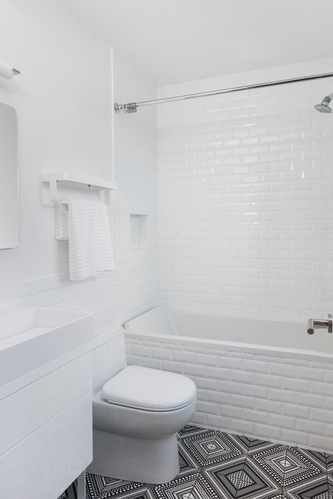 Modern inredning av ett mellanstort badrum för barn, med ett nedsänkt handfat, vita skåp, bänkskiva i akrylsten, ett platsbyggt badkar, en dusch/badkar-kombination, en vägghängd toalettstol, vit kakel, keramikplattor, vita väggar och klinkergolv i keramik