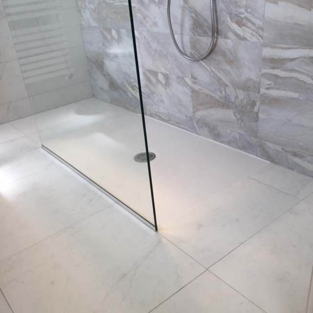 Immagine di una stanza da bagno con doccia minimalista di medie dimensioni con doccia aperta, WC sospeso, piastrelle multicolore, piastrelle in gres porcellanato, pareti bianche, pavimento in gres porcellanato, lavabo a bacinella e top piastrellato