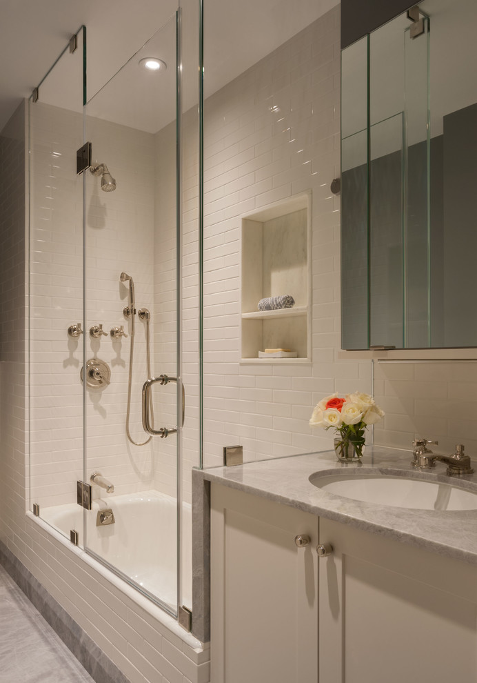 Bathroom - mid-sized contemporary stone slab marble floor and gray floor bathroom idea in New York with an undermount sink, recessed-panel cabinets, white cabinets, marble countertops, a one-piece toilet, white walls and a hinged shower door