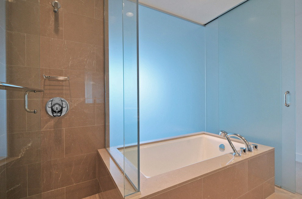 Cette photo montre une salle de bain tendance avec une baignoire encastrée, une douche d'angle et un carrelage beige.