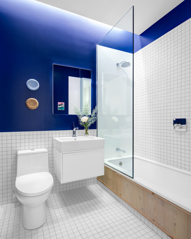 Cette image montre une salle de bain design avec un placard à porte plane, des portes de placard blanches, une baignoire en alcôve, un combiné douche/baignoire, un carrelage blanc, mosaïque, un mur bleu, un sol en carrelage de terre cuite, un plan vasque, un sol blanc, aucune cabine, meuble simple vasque et meuble-lavabo suspendu.