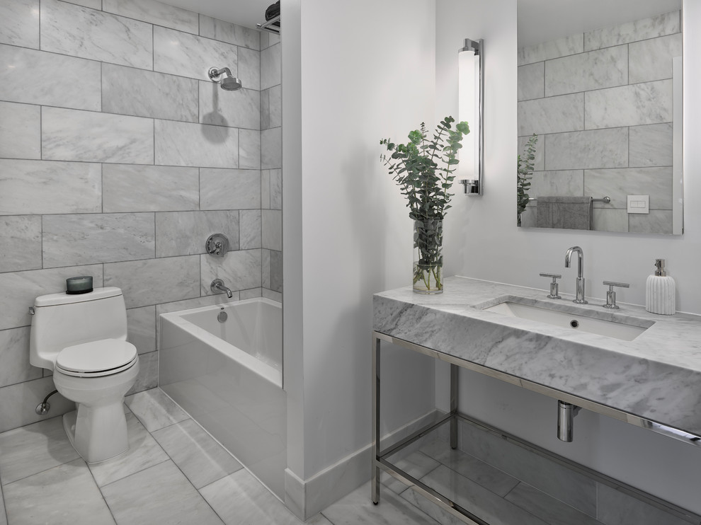 Mid-sized trendy gray tile and marble tile marble floor and gray floor bathroom photo in New York with open cabinets, a one-piece toilet, white walls, an undermount sink, marble countertops and gray countertops