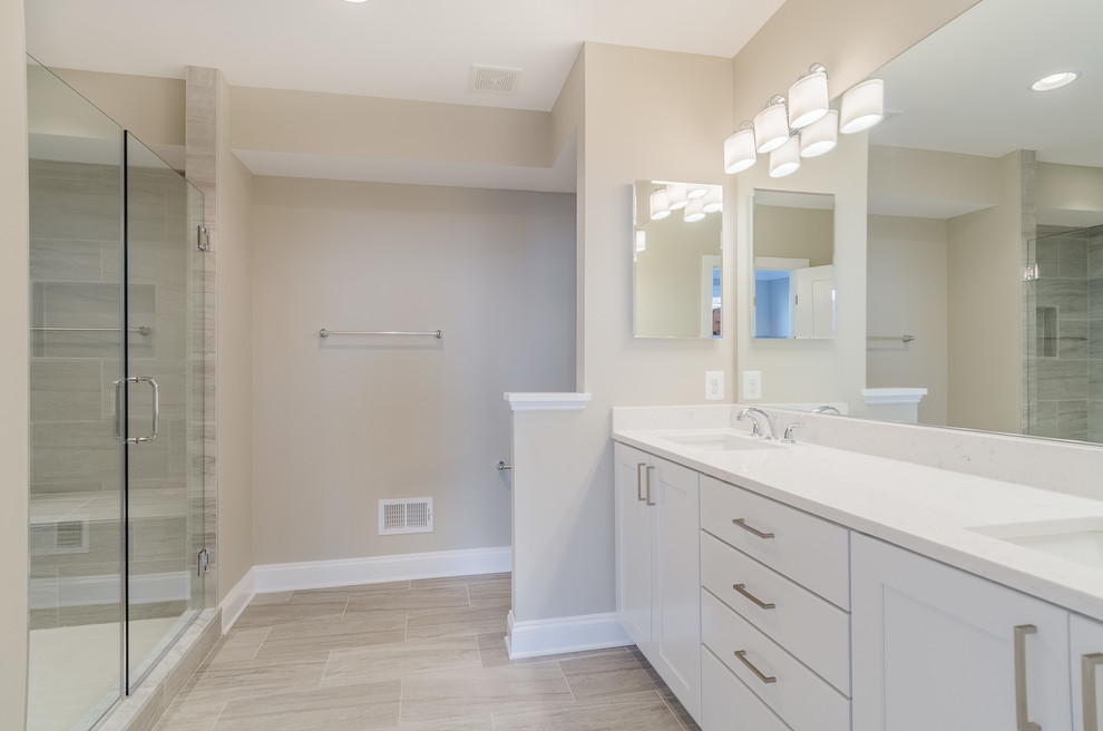 Large urban 3/4 beige tile and porcelain tile porcelain tile and gray floor bathroom photo in Baltimore with shaker cabinets, white cabinets, beige walls, an undermount sink, quartz countertops, a two-piece toilet and a hinged shower door