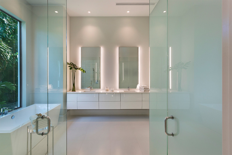 Inspiration for a medium sized contemporary ensuite bathroom in Other with flat-panel cabinets, white cabinets, a freestanding bath, grey walls, a submerged sink, white floors, white worktops, a built-in shower, a one-piece toilet, white tiles, porcelain tiles, porcelain flooring, solid surface worktops and a hinged door.