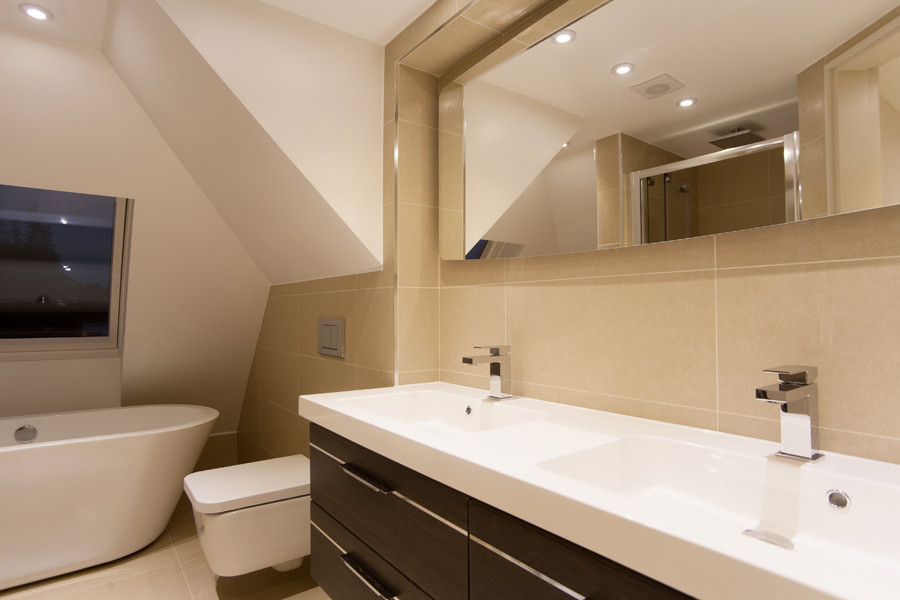 Photo of a contemporary ensuite bathroom in London with an integrated sink, a freestanding bath, a corner shower, a wall mounted toilet, porcelain tiles, beige walls and porcelain flooring.