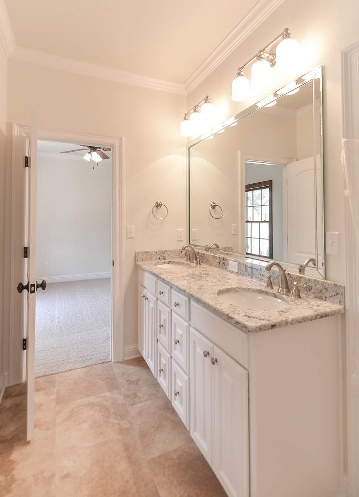 Esempio di una stanza da bagno classica con lavabo sottopiano, ante con bugna sagomata, ante bianche, top in granito, vasca/doccia, piastrelle beige e pareti beige