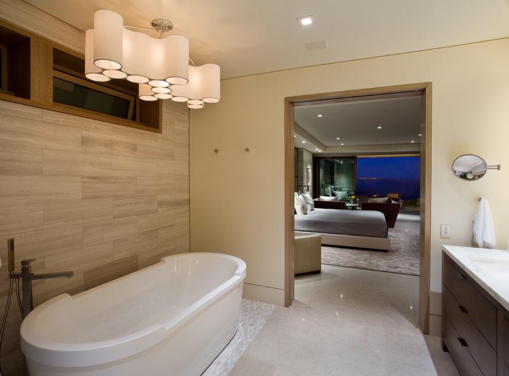 Inspiration for a large modern ensuite bathroom in Orange County with flat-panel cabinets, dark wood cabinets, a freestanding bath, a corner shower, beige tiles, porcelain tiles, beige walls, ceramic flooring, a submerged sink, engineered stone worktops, beige floors and a hinged door.