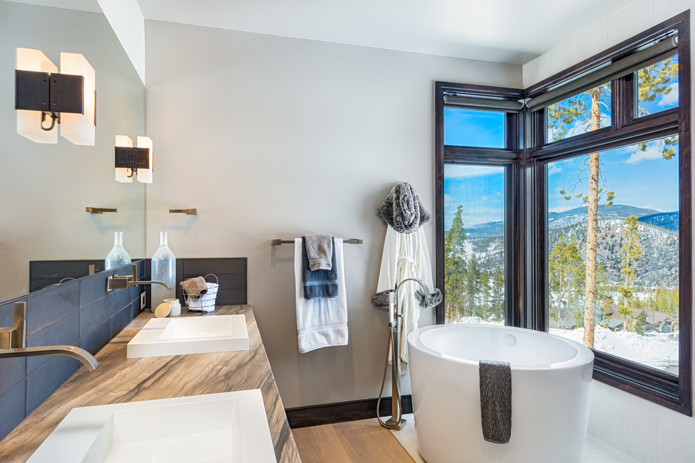 Uriges Badezimmer En Suite mit japanischer Badewanne, grauen Fliesen, grauer Wandfarbe, hellem Holzboden, Aufsatzwaschbecken und bunter Waschtischplatte in Denver
