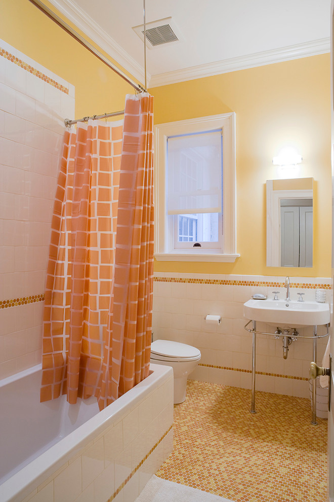 Immagine di una stanza da bagno tradizionale con lavabo a consolle, vasca ad alcova, vasca/doccia, piastrelle arancioni, pareti gialle, pavimento con piastrelle a mosaico e pavimento arancione