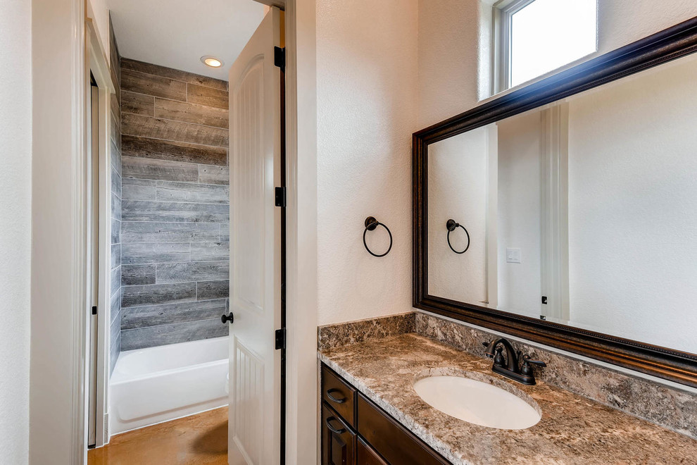 Drop-in bathtub - traditional beige tile, brown tile and mosaic tile concrete floor and beige floor drop-in bathtub idea in Austin with raised-panel cabinets, dark wood cabinets, a two-piece toilet, beige walls, an undermount sink and granite countertops
