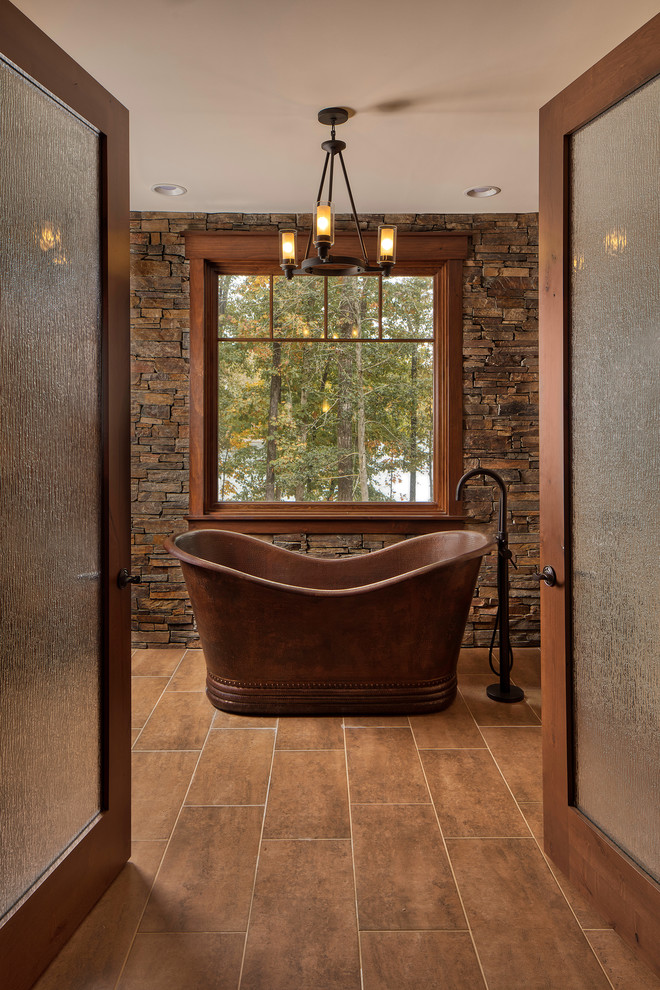 Rustikales Badezimmer mit freistehender Badewanne und braunem Boden in Sonstige