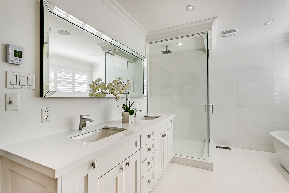 Design ideas for a large traditional ensuite bathroom in Toronto with a submerged sink, shaker cabinets, white cabinets, engineered stone worktops, a freestanding bath, a double shower, a two-piece toilet, white tiles, white walls and marble flooring.