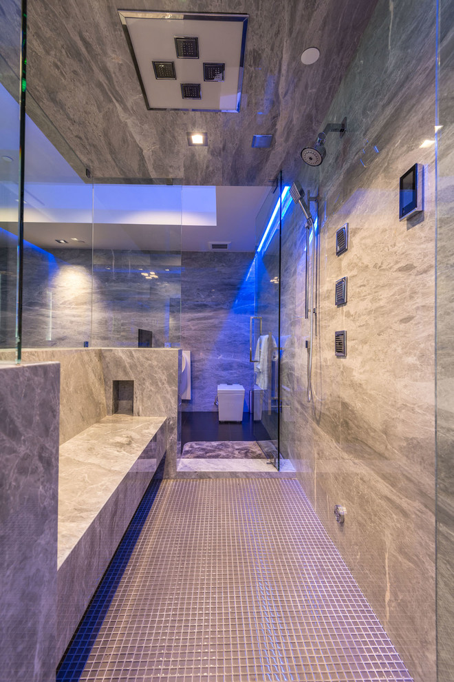 Cette image montre une très grande salle de bain principale minimaliste avec un espace douche bain, WC à poser, un carrelage gris, des dalles de pierre, un mur gris, un sol en carrelage de terre cuite, un sol gris, une cabine de douche à porte battante, un banc de douche et meuble-lavabo encastré.