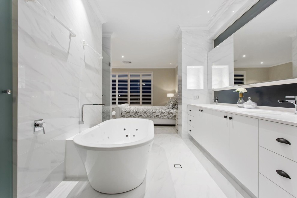 Idee per una stanza da bagno design di medie dimensioni con ante lisce, ante bianche, vasca freestanding, pareti bianche, lavabo da incasso e pavimento bianco